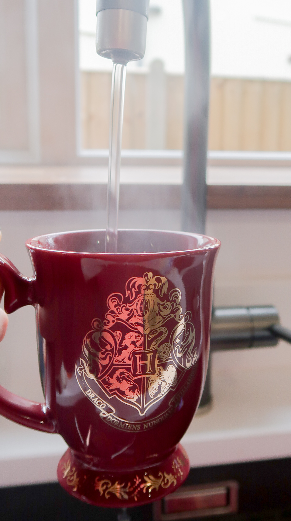 Harry Potter Hogwarts crest mug being filled up using hot water tap.