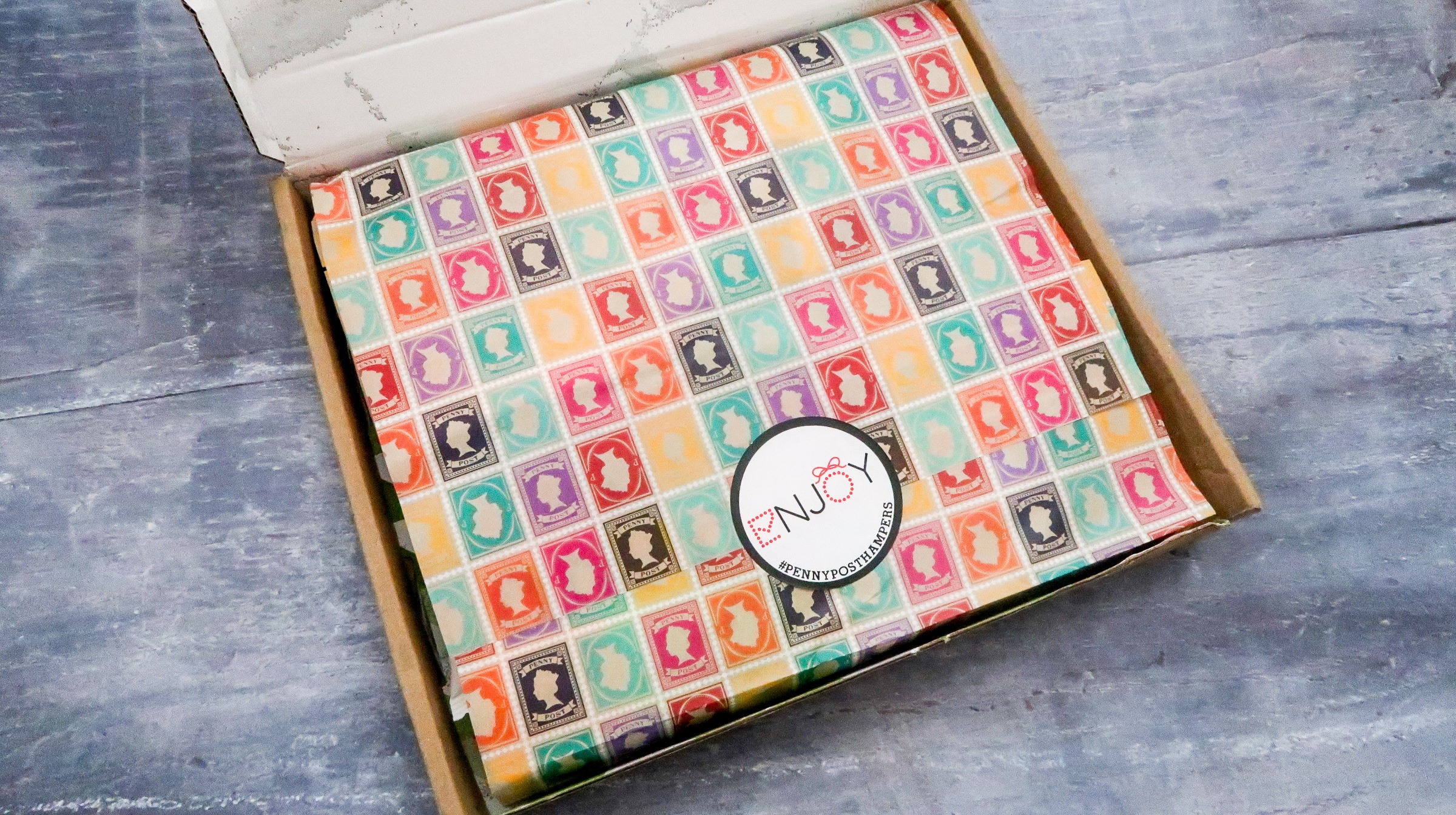 inside packaging of letterbox hamper grid of stamps in multi colours with circular branded sticker