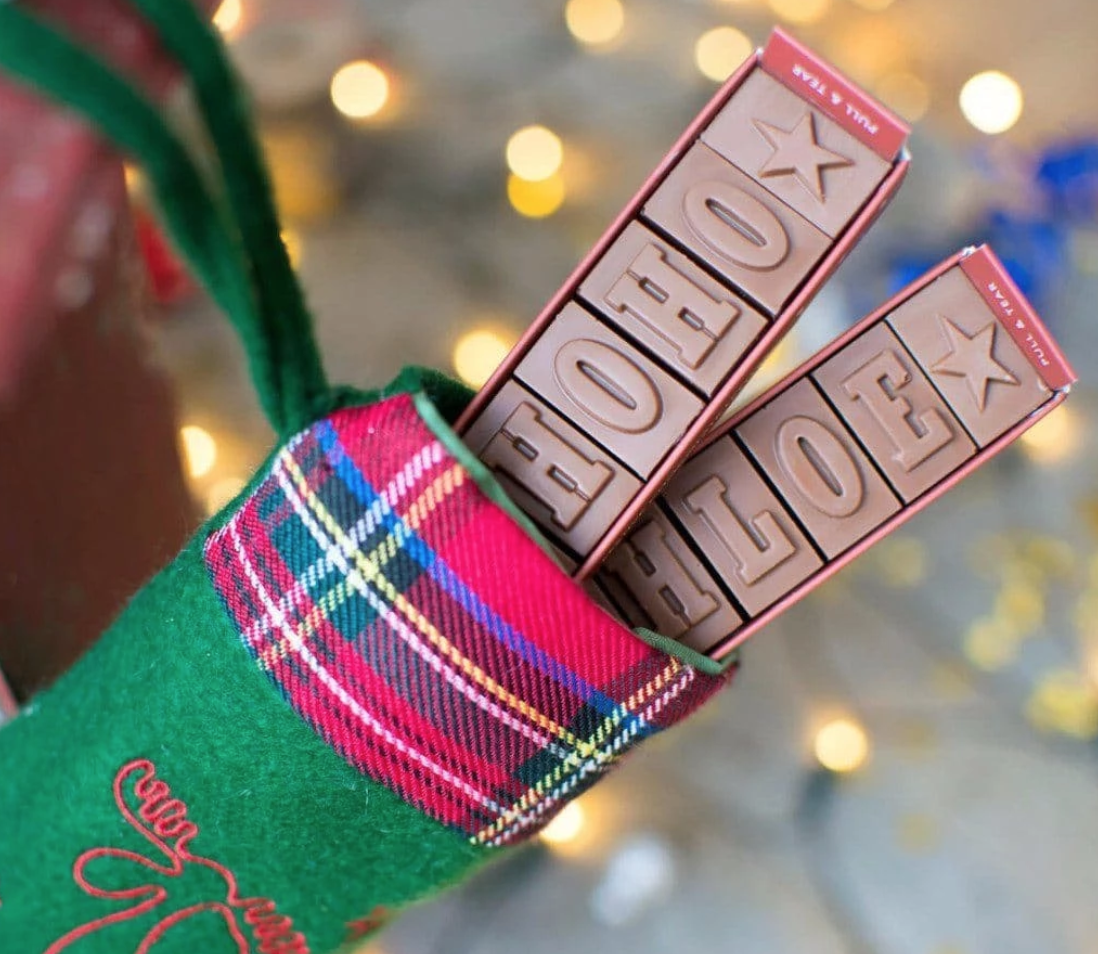 morse toad personalised chocolate names poking out the top of a stocking at christmas